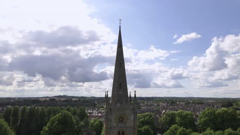 Holy-Trinity-church-aerial-view-orbiting-steeple-and-rural-Stratford-Upon-Avon-countryside-blue-sky-landscape