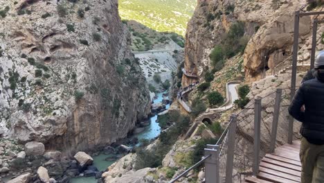 People-hiking-with-helmets-the-famous-caminito-del-rey-between-mountain-cliffs-in-Malaga,-Spain