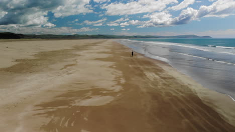 Distant-View-Of-A-Man-Walking-On-Sandy-Shore-Of-Porangahau-Beach-In-North-Island,-New-Zealand