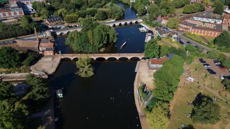 Establishing-aerial-view-flying-reverse-over-Clopton-historical-town-archway-canal-bridge,-Stratford-Upon-Avon,-England