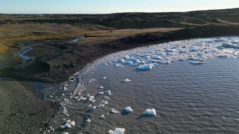 Scattered-Chucks-of-Iceberg-Floating-at-the-Coast,-Sunny-Day-Aerial