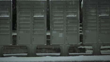 Low-angle-tilt-up-post-mail-boxes-on-heavy-snowfall-winter-night
