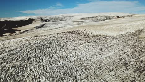 Aerial-panoramic-landscape-view-over-the-textured-ice-surface-of-an-icelandic-glacier,-on-a-bright-sunny-day
