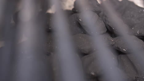 Slider-move-on-close-up-BBQ-charcoal-briquettes-with-grilling-grates-in-foreground