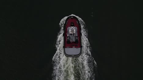 An-aerial-view-high-above-a-lone-tugboat-on-a-cloudy-morning-in-the-Hudson-River,-near-Brooklyn,-NY