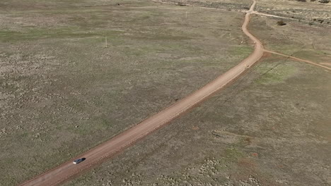 Drone-shot-of-car-driving-on-dirt-road-in-Willcox,-Arizona,-wide-downward-angle-aerial-shot