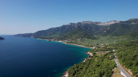 Drone-View-Over-Kinira-View-Point-With-High-Mountain-Peaks,-Lush-Green-Vegetation,-Mountain-Road-And-Tropical-Beaches-In-The-Distance,-Thassos-Island,-Greece