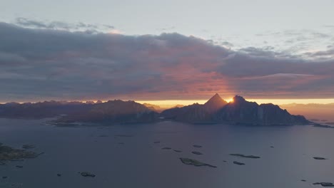 Über-Den-Bergen-Auf-Den-Lofoten-In-Norwegen-Bricht-Ein-Wunderschöner-Sonnenaufgang-über-Den-Berggipfeln-Auf,-Der-über-Dem-Wasser-Und-Den-Gipfeln-Wunderschöne-Farben-Verbreitet