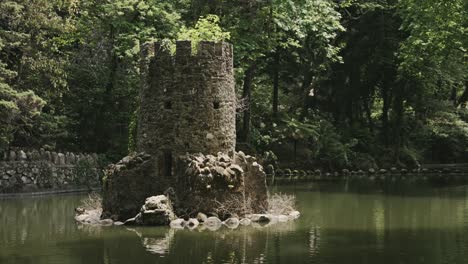 Castle-tower-remains-surrounded-by-water-and-dense-forest,-handheld-view