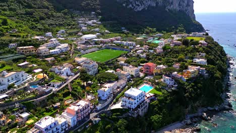 Football-Field-Surrounded-With-Buildings-In-The-Island-Of-Capri,-Italy---aerial-drone-shot
