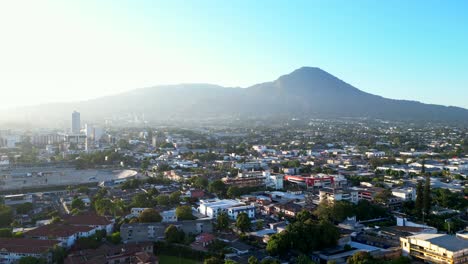 Drone-shot-San-Salvador-city-with-mountains-and-volcanoes-in-distance
