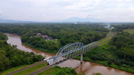 Train-bridge-crossing-dirty-river-and-connecting-rural-villages-in-Indonesia---Aerial-view