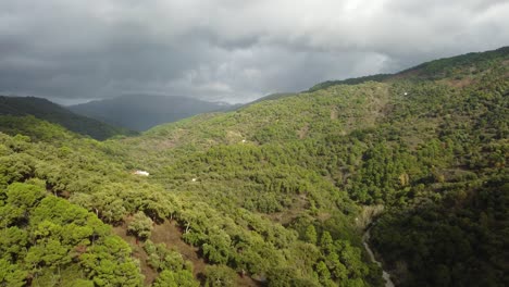 Stormy-clouds-casting-shadow-on-woodland-landscape-in-Spain,-aerial-view