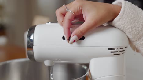 Female-hand-changing-speed-setting-of-a-stand-mixer,-closeup-static-shot