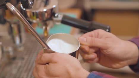 Preparing-steamed-milk-in-stainless-steel-milk-jug