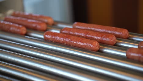 Nahaufnahme-Von-Würstchen,-Die-Auf-Einer-Hot-Dog-Grillmaschine-In-Einem-Fast-Food-Restaurant-Rollen