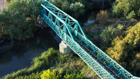 Seitliche-Antenne-Einer-Grünen-Eisenbahnbrücke,-Verloren-In-Der-Spanischen-Natur,-Sonnenaufgang