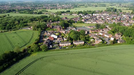 Zoom-in-drone-shot-from-the-air-of-the-landscape-in-cronton-village-with-view-of-the-fields-and-beautiful-idyllic-residential-houses