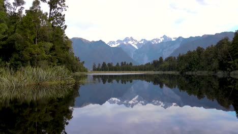 Die-Atemberaubende-Alpenlandschaft-Spiegelt-Sich-Im-Lake-Matheson-Wider,-Der-Von-üppigen-Einheimischen-Wäldern-Umgeben-Ist