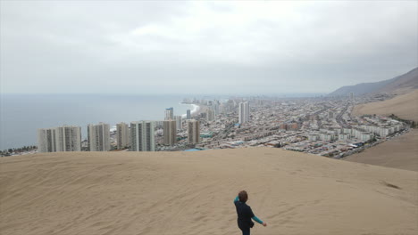 Aerial-shot-of-a-tourist-taking-video-for-reaching-the-top-of-the-famous-Cerra-Dragon-Dune-at-Tarapaca,-Iquique-Chile-Latin-America