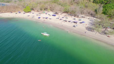 Rückwärts-Drohnen-Dolley-Aufnahme-Von-Menschen,-Die-Den-Sommer-An-Einem-Strand-In-Costa-Rica-Genießen