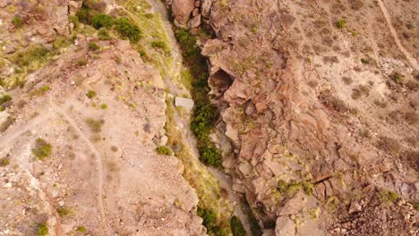 Natural-ravine-with-flowing-river-bellow,-aerial-orbit-view