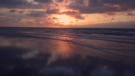 Slow-motion-aerial-shot-of-waves-in-Itanhaem-beach-in-sunrise,-perfect-sky