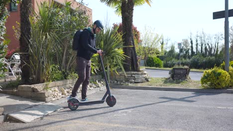 European-Man-Wearing-Helmet-And-Backpack-Rides-On-An-Electric-Scooter-On-A-Sunny-Day