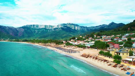 Panoramic-Aerial-View-Of-Golden-Beach-With-Towering-Mountain-Peaks,-Beautiful-Beachfront-And-Lush-Vegetation,-Thassos-Island,-Greece,-Europe