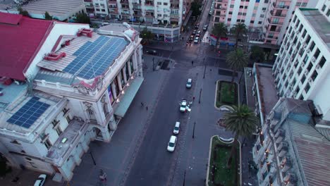 Luftaufnahme-Mit-Blick-Auf-Das-Stadttheater-Von-Santiago-Mit-Einem-Schwarm-Tauben,-Die-über-Den-Straßen-Der-Stadt-Fliegen