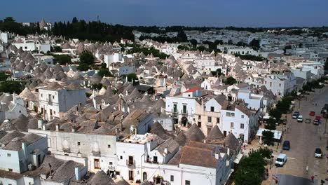 Flying-over-the-heritage-site-of-Alberobello-with-a-drone-by-a-sunny-day,-birds-flying-arround