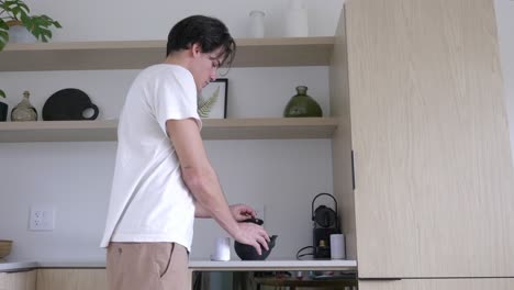 Young-Man-Pours-Tea-Powder-Into-Teapot,-Making-Tea-In-The-Morning-At-The-Hotel-Room
