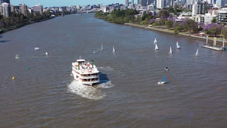 Drone-shot-flying-backwards-revealing-many-small-boats-having-a-sailing-race-on-the-Brisbane-River,-near-West-End-and-Toowong