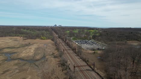 An-aerial-view-of-a-train-traveling-off-far-in-the-distance-in-The-Bronx,-New-York-on-a-sunny-morning