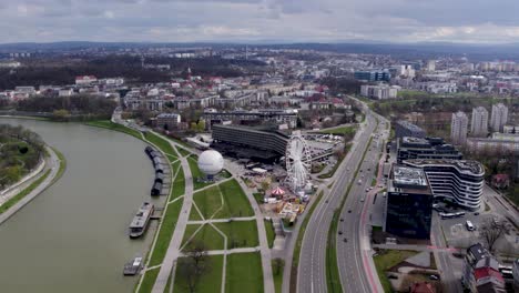 Aerial-Shot-of-City-Highway,-Ferris-Wheel-and-Urban-Scenery