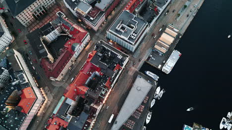 Top-down-tracking-shot-of-a-small-port-with-boats,-houses-and-streets,-some-cars-are-seen-along-a-river,-daytime,-no-people,-aerial-view