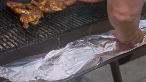 Man-foil-wraps-brown-sugar-rub-coated-BBQ-ribs-and-places-on-pit