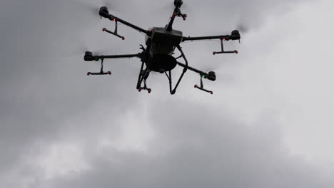 Drone-De-Agricultura-Profesional-Volando-Bajo-Un-Cielo-Nublado-Oscuro,-ángulo-Bajo,-Cámara-Lenta