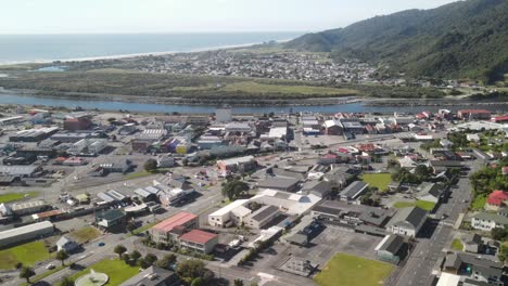Aerial-pull-back-of-Greymouth-town-centre,-Cobden-suburb,-river-and-coastal-landscape