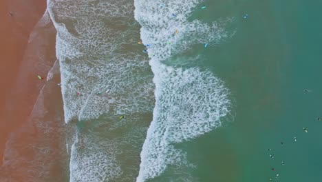 Von-Oben-Nach-Unten-Blick-Auf-Farbenfrohe-Surfer,-Die-In-El-Palmar,-Spanien,-Lernen,-Wellen-Zu-Fangen
