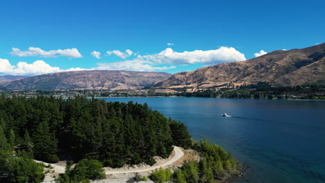 Aerial-footage-of-boat-sailing-on-Wanaka-Lake-with-forest-on-shore