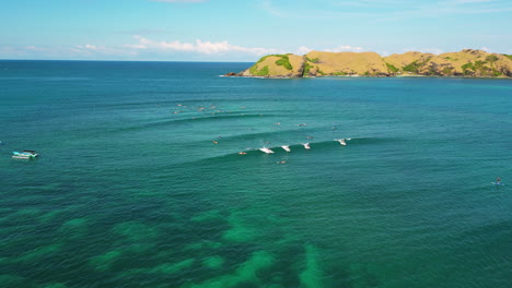 Aerial-circling-unrecognizable-surfers-riding-waves-of-Kuta,-Lombok,-Indonesia