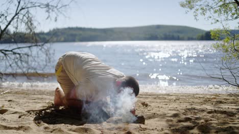 Man-Blowing-Firewood-On-The-Campsite-In-The-Beach
