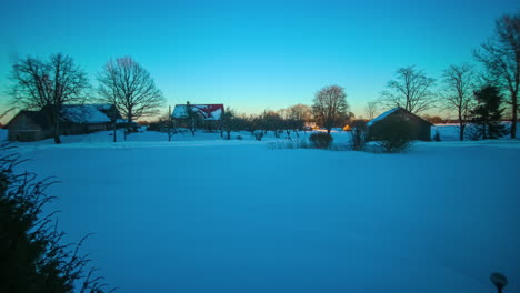 Timelapse-shot-throughout-the-day-to-night-of-wooden-village-cottage-silhouette-on-snow-in-the-rural-countryside