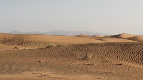 Wüstenlandschaft-Im-Nahen-Osten-In-Der-Nähe-Von-Dubai-In-Den-Vereinigten-Arabischen-Emiraten-Mit-Sanddünen-Und-Fernen-Bergen