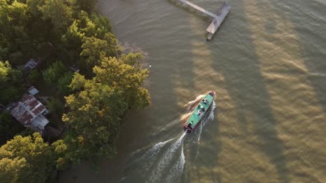 Aerial-overhead-shot-of-bus-boat-floating-on-Parana-River-during-golden-sunset-time---Argentina,South-America---Orbiting-shot