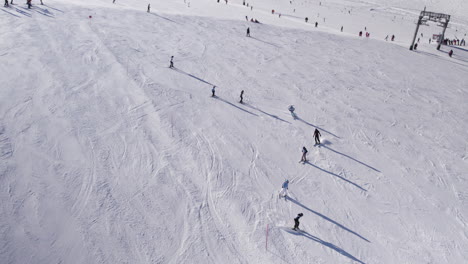 Row-of-people-skiing-down-a-ski-slope-on-Kizsteinhorn-mountain-in-Austria-in-winter