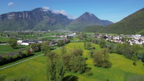 Stadt-Eingebettet-In-Schweizer-Grün,-Umgeben-Von-Majestätischen-Bergen,-Luftaufnahme