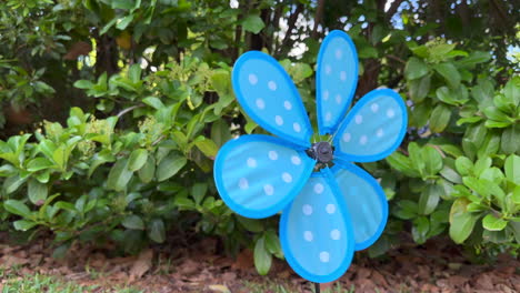 Blue-pinwheel-barely-spinning-from-light-wind-breeze,-close-up
