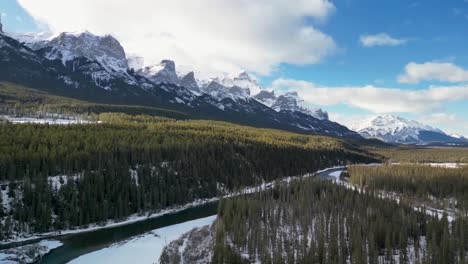 Aerial-of-Bow-River-with-forest-and-mountains,-Alberta,-Canada